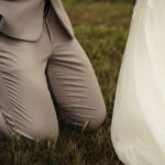 a bride and groom holding hands in the grass