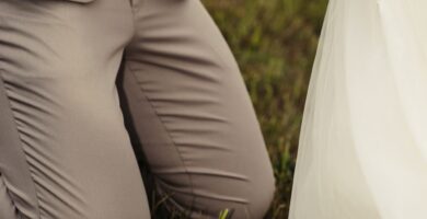 a bride and groom holding hands in the grass